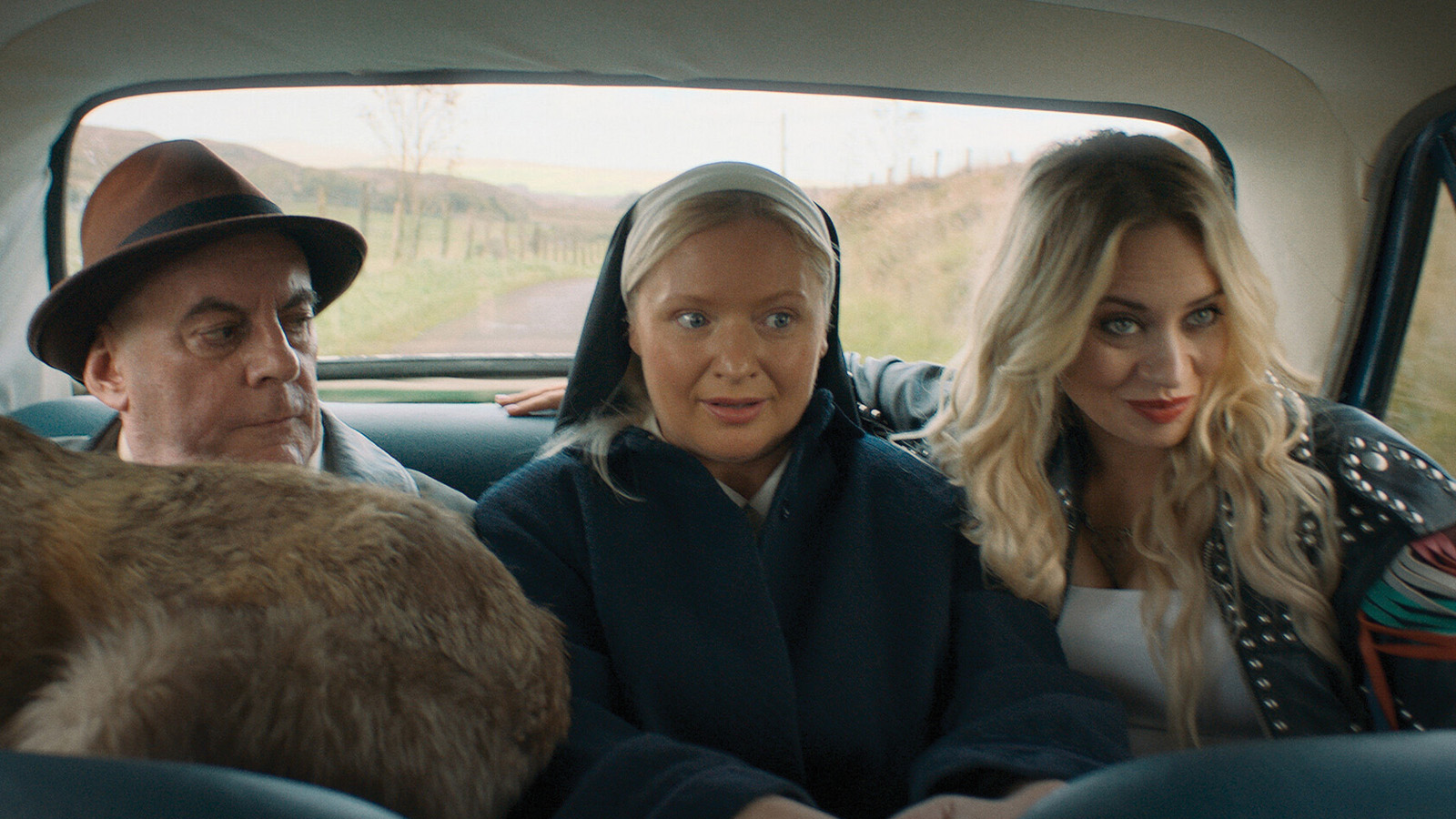 The Spin movie still showing a goat, a man, a nun, and a woman sitting in the back seat of a car.